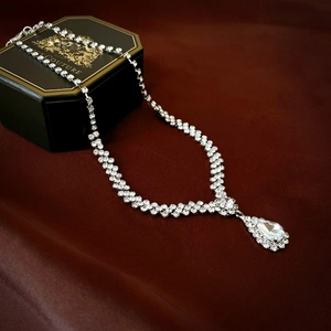 Close-up of a silver rhinestone Y-necklace with a sparkling teardrop crystal pendant