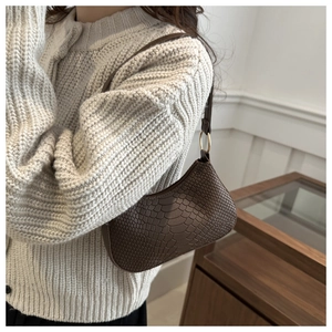 Detail of dark brown hobo bag featuring snake skin texture and gold ring hardware
