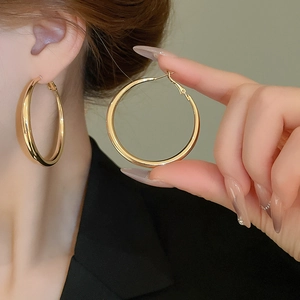 Close-up of elegant gold hoop earrings worn on ear with polished metallic finish