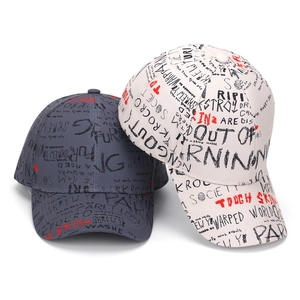 Detail of printed graffiti text on grey and beige cotton twill baseball caps