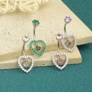Macro shot of silver heart belly rings with sparkling colorful zircon stones on stone slabs