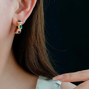 Vintage gold geometric C-shaped earrings with colorful gemstones on a black background