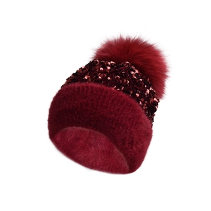 Detailed close-up of wine red sequined knit beanie with fluffy faux fur pom-pom