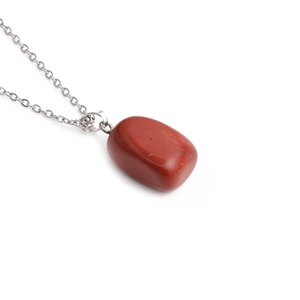 Macro view of natural red gemstone pendant with silver metal chain on white background