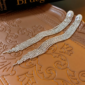 Macro shot of luxurious silver needle long tassel earrings with sparkling zircon crystals