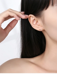 Detailed close-up of rose gold bow earrings with sparkling cubic zirconia on model ear