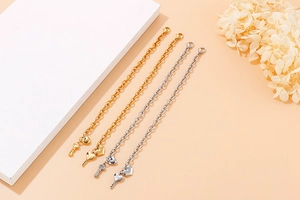 Detail view of gold and silver bracelets featuring heart and key charms on a warm background