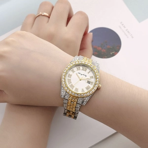 Close-up of gold and silver women's watch with crystal-encrusted bezel and Roman numerals