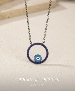 Detail of gunmetal evil eye pendant with blue crystals and minimalist chain necklace