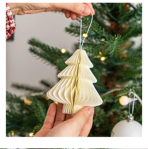 Detail of a creamy white honeycomb paper Christmas tree ornament with a hanging rope