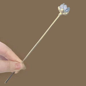 Macro detail of a golden vintage hair pin featuring a light blue lotus flower ornament