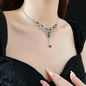 Silver necklace with green gems and diamond tassels worn on neck for luxury look