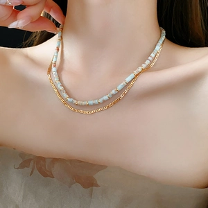 Close-up of a double-layered ethnic beaded necklace with blue stones and a gold chain