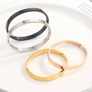 Close-up of four polished stainless steel hinged bangles in gold, silver, rose gold and black