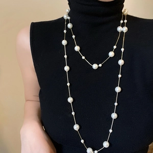 Detailed view of elegant long layered pearl necklace on a black high neck top