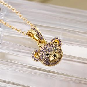 Macro detail of bear pendant necklace with purple zircons on 18K gold chain