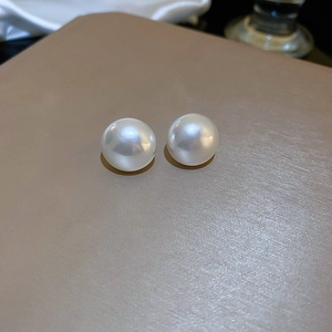 Classic 8-10mm round white faux pearl stud earrings with a glossy finish on beige background