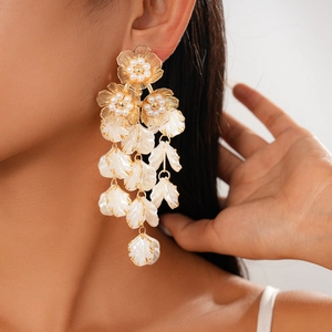 Detail of flower earrings with gold petals, shell tassels and pearl center accents