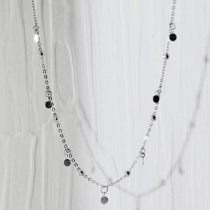 Elegant minimalist silver choker necklace with shimmering round discs and beads on a white background