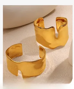 Detail of irregular wave-edged gold cuff bracelets with hammered texture and mirror finish