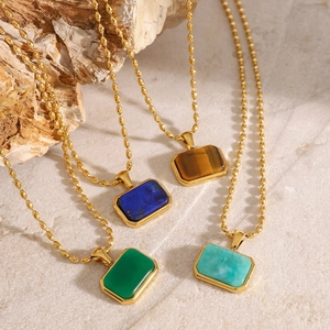 Minimalist gold tiger eye stone pendant necklace set displayed on natural stone and wood