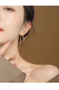 Close-up of golden heart-shaped S925 silver earring on a model for an elegant look