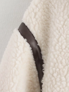 Detail der cremefarbenen Teddy-Fleece-Jacke mit dunkelbraunen Lederpaspeln am Rand