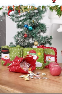 Felt Christmas gift bags with Santa and snowman embroidery on a festive wooden table