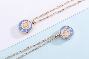 Detail of rose gold zodiac necklaces featuring blue enamel coin pendants with constellations