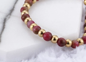 Macro shot of gold-plated titanium beads and red garnet stones on an elastic bracelet