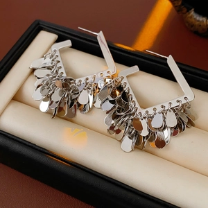 Dettaglio di orecchini geometrici in argento con nappine a paillettes tonde pendenti