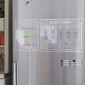 Detail of magnetic acrylic weekly planner with colored markers on a stainless steel fridge