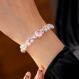 Close-up of elegant double-strand pearl bracelet with pink gemstone on woman's wrist