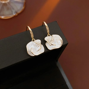 Macro detail of vintage gold-plated flower earrings with white mother-of-pearl inlay