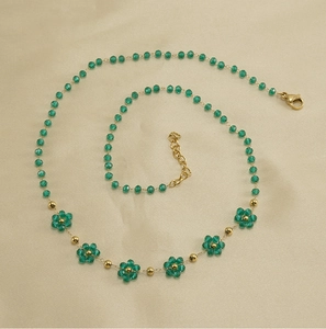 Close-up of a green crystal flower necklace with a gold chain and lobster clasp closure