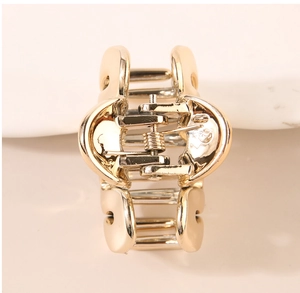Detailed close-up of a mini golden metal hair claw clip with polished surface and spring