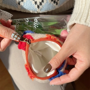 Detail view of colorful plush bucket bag with orange zipper and soft white lining