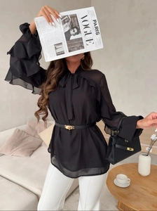 Detail of black chiffon blouse showing tiered ruffle sleeves and elegant bow neckline