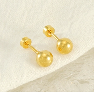Detail of gold screw-back ball earrings showing the polished finish and secure closure