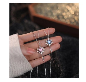 Detailed view of silver key pendant necklace with pink and blue heart-shaped zircons