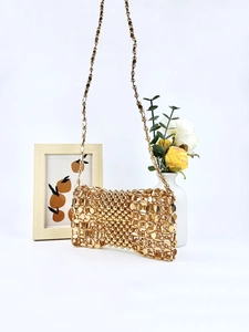 Golden handmade metallic beaded woven crossbody bag with hollow texture on white background