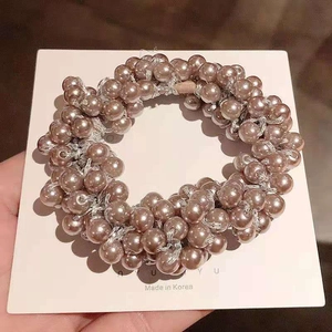 Close-up of handmade champagne pearl hair tie on a white card with elastic band detail