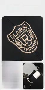 Detail of shield embroidery and adjustable metal buckle on a black twill baseball cap