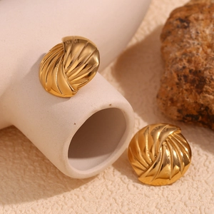 Dettaglio di orecchini a lobo in acciaio placcato oro 18K con design a disco con texture a spirale