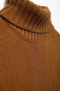 Close-up of caramel knitted sweater vest showing high collar and thick cable knit texture