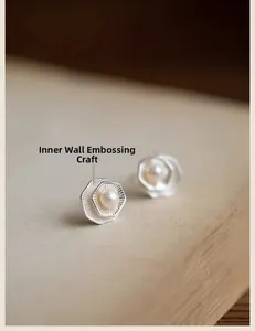 Detailed view of geometric silver lotus earrings with hammered texture and pearl center