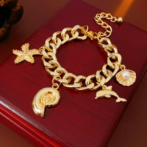 Detail of gold ocean charm bracelet with starfish and pearl shell on wooden box