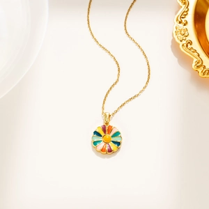 Détail d'une chaîne en acier titane doré avec un pendentif marguerite en émail coloré