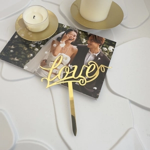Close-up of golden acrylic love cake topper for romantic wedding and party decoration