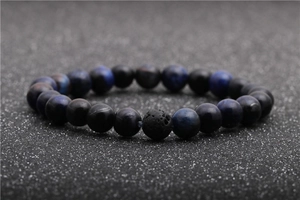 Macro shot of tiger eye and lava stone bead bracelet in deep blue and black tones